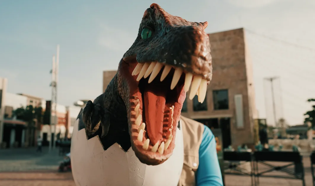 A playful cinematic frame with a dinosaur model